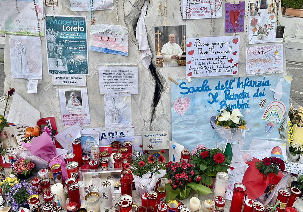 The statue of St. John Paul II at Gemelli Hospital is surrounded by dozens of lit candles, hanging rosaries and drawings or photographs of Francis with messages of all sizes, shapes and colors, wishing him a speedy recovery, mostly written by children from nearby elementary schools in the Roman neighborhood of Balduina, where Gemelli is located. (NCR photo/Camillo Barone)