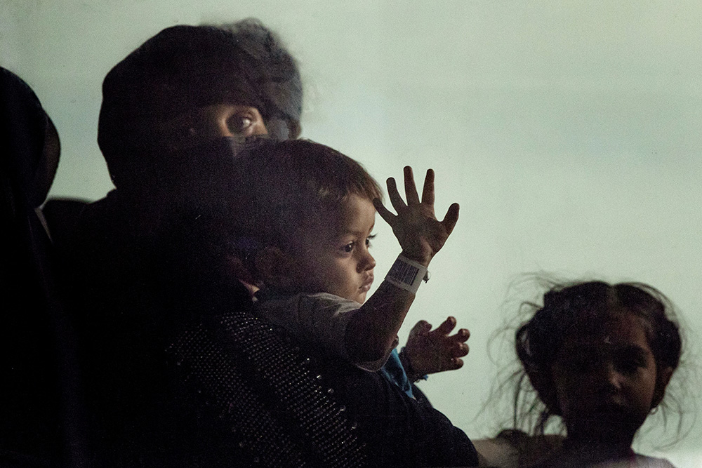 Families evacuated from Kabul, Afghanistan, sit in a bus after they arrived at Washington Dulles International Airport, in Chantilly, Va., Aug. 31, 2021. Commonwealth Catholic Charities in Virginia is among local Catholic Charities agencies that have challenged the federal government's abrupt suspension of the refugee resettlement program on Jan. 24, 2025. (AP/Gemunu Amarasinghe)