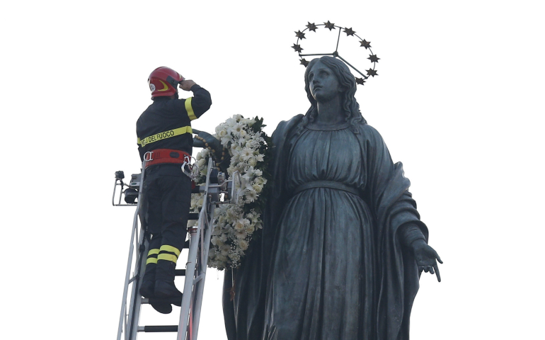 A firefighter salutes after placing a wreath on a statue of Mary overlooking the Spanish Steps in Rome Dec. 8, the feast of the Immaculate Conception. Rome's firefighters have observed the tradition every year since 1857. (CNS photo/Paul Haring)