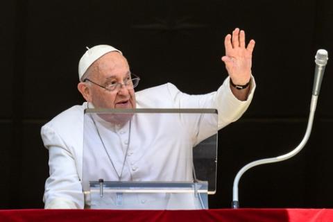 Pope Francis, at lectern, waves to people from balcony. 