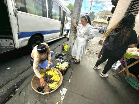 La Hna. Silvia Flores habla con una señora que vende fruta, el 25 de enero de 2024, sobre el nuevo proyecto —Sembrando Semillas de Esperanza— de Colegio Eucarístico dirigido por las Hermanas Mercedarias del Santísimo Sacramento en San Salvador, El Salvador. (Foto: GSR/ Rhina Guidos)  