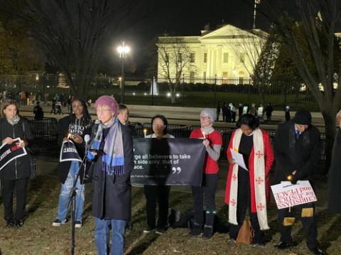 Bishop stands in front of White House at night. 