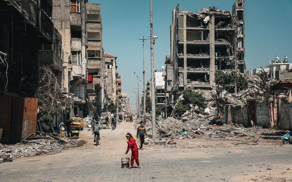 A child carries a bucket along a row of destroyed buildings March 16 in Gaza City. (OSV News/Courtesy of Caritas Poland)