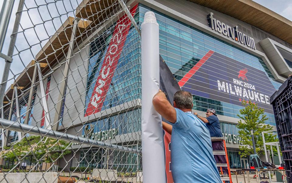 Workers attach signage to security fencing on July 10, ahead of the 2024 Republican National Convention at the Fiserv Forum in Milwaukee. (AP/Alex Brandon)