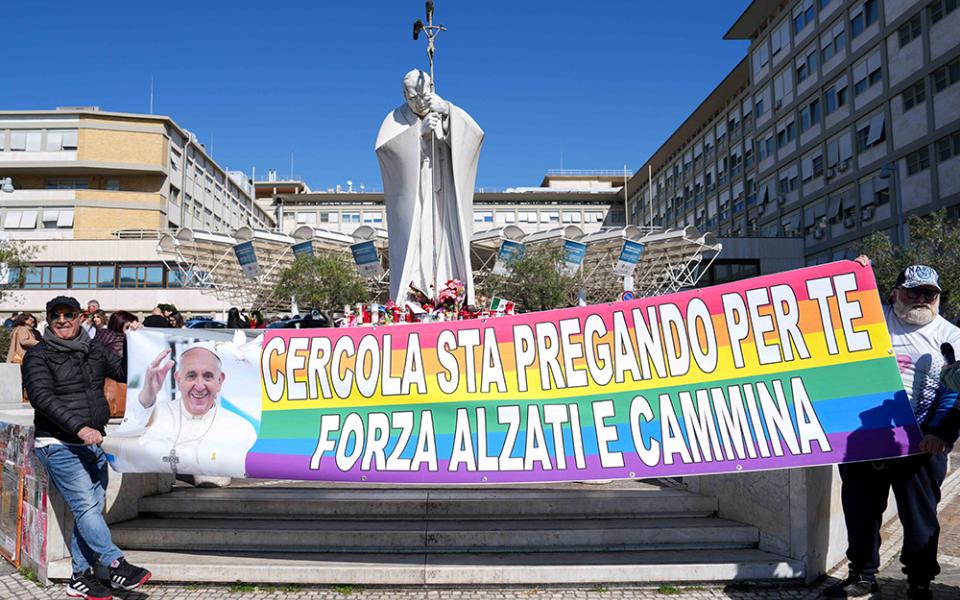 People hold a banner with a greeting in Italian for Pope Francis outside Rome's Gemelli Hospital on March 6. The banner says, "Cercola is praying for you. Stay strong, rise and walk." The phrase "rise and walk" is from the Acts of the Apostles, and Cercola is a town near Naples. (CNS/Lola Gomez)