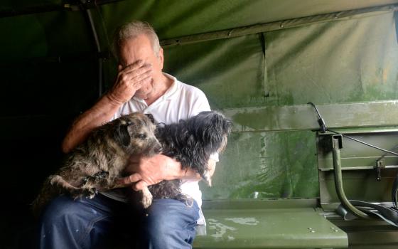 An evacuee holding two dogs becomes emotional after his Aug. 29 rescue by Texas National Guardsmen from severe flooding from Tropical Storm Harvey in Houston. (CNS/Army National Guard handout via Reuters/U.S. Army Capt. Martha Nigrelle)