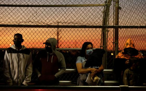 Migrants in the "Remain in Mexico" program line up at the Paso del Norte Mexico-U.S. border bridge in Ciudad Juarez, Mexico, April 21 to reschedule their United States immigration hearings during the coronavirus pandemic. (CNS/Reuters/Jose Luis Gonzalez)