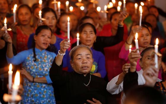 Women hold candles at a church Oct. 26, 2019, in My Khanh, Vietnam. The service was for 39 people found dead in the back of a truck at the Port of Tilbury Oct. 23, in Essex, England. (CNS/Reuters/Kham) 