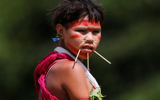Pierced and painted girl in traditional garb looks at camera. 