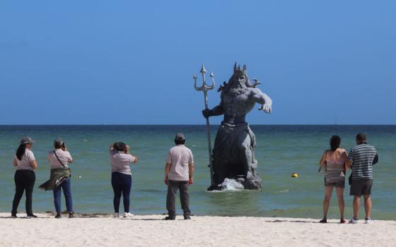 Tourists take pictures of a Poseidon sculpture before the arrival of Hurricane Beryl in Progreso, Yucatan, Mexico, July 4.
