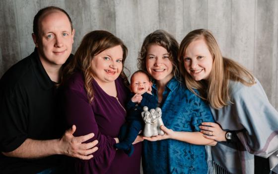 Phil and Meghan Young hold their son Henry with their surrogate mother Rachelle Simon, and her wife Ariell Watson Simon, in April 2021. 