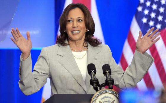 Harris raises hands, smiling, as she speaks at a lectern. 