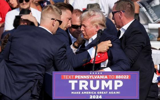 Republican presidential candidate and former U.S. President Donald Trump is assisted by guards during a campaign rally after shots were reportedly fired at the Butler Farm Show in Pennsylvania July 13, 2024. A local prosecutor says the suspected gunman and at least one attendee are dead. 