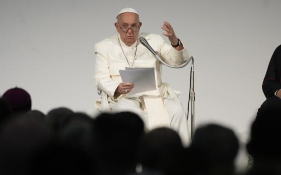 Pope Francis, seated, reads remarks