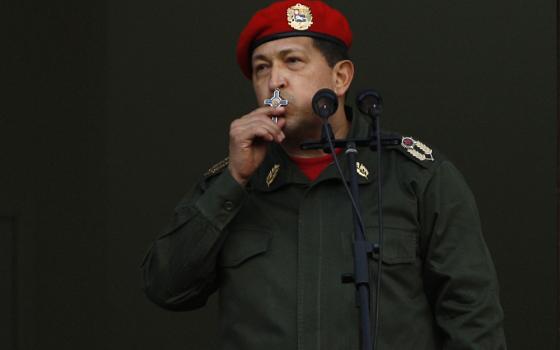 Chavez, in military regalia, kisses crucifix. 