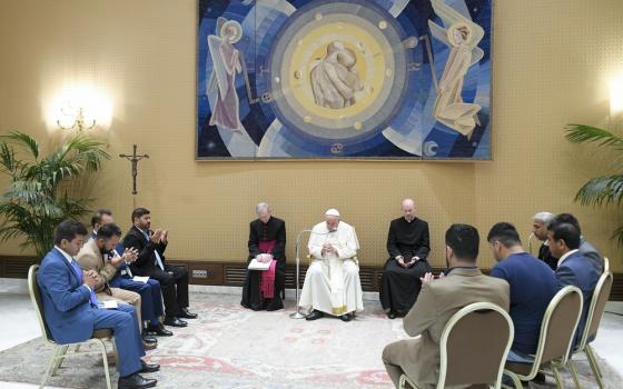 Francis seated, flanked by prelates, seated in circle around pope are association representatives. 