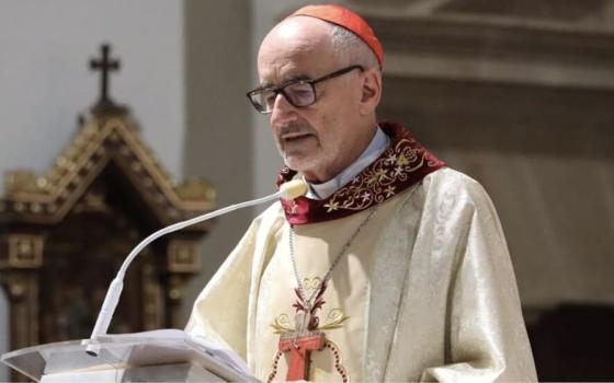 Czerny, vested for Mass, speaks from lectern. 