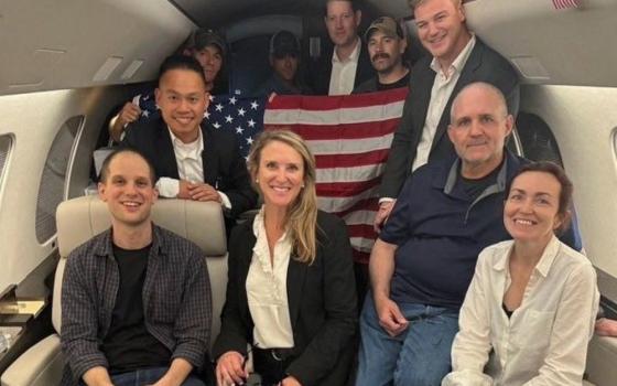 Evan Gershkovich, Paul Whelan and Alsu Kurmasheva, who were detained in Russia, pose with others aboard an aircraft after they were released, in this undated handout photograph obtained on Aug. 1. 