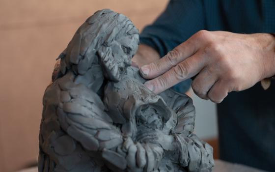 Canadian Catholic artist Tim Schmalz, a native of St. Jacobs, Ontario, sculpts a figure of Jesus embracing a homeless person Sept. 27, 2022, during the annual national gathering of Catholic Charities agencies at the Hilton Baltimore Inner Harbor on Sept. 27-29. (CNS/Catholic Review/Kevin J. Parks)