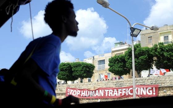 A man walks past a banner reading "Stop Human Trafficking!" in 2018 in Valletta, Malta. (OSV News/Reuters/Guglielmo Mangiapane)