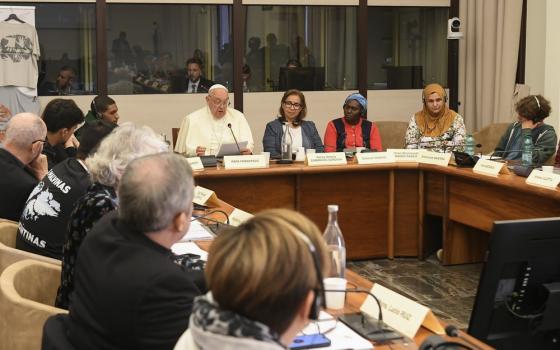 Pope sits at head of U-shaped table reading remarks.