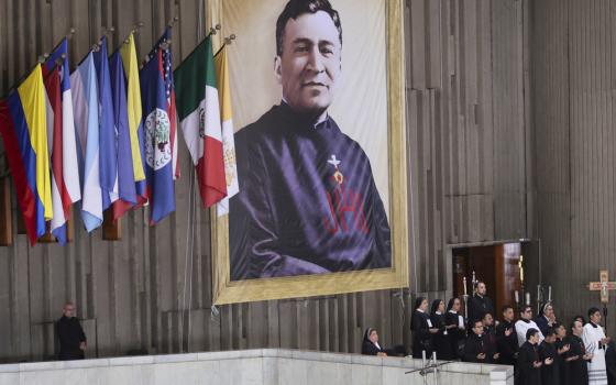 Large banner hangs on wall beside various flags. 