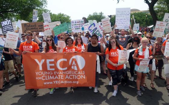 Young people march with banner and signs.