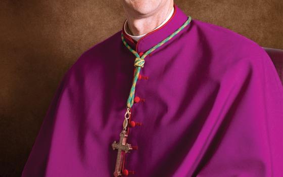 Formal portrait of the bishop in choir dress smiling. 