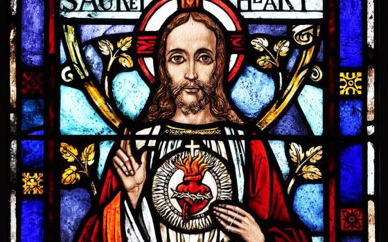 Stained glass image of Jesus bearing his Sacred Heart. 