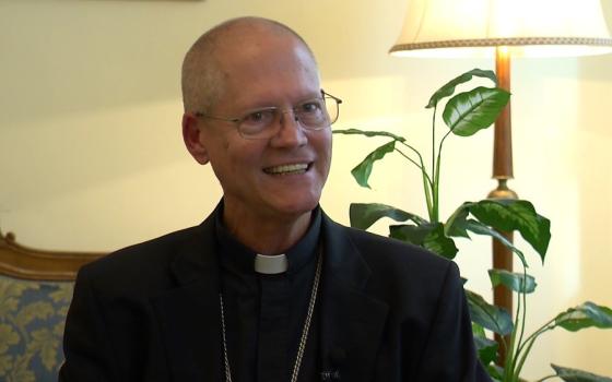 Etienne wears plain black clerics and smiles.