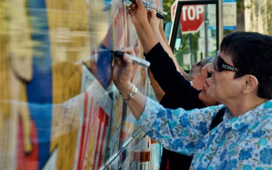 People sign the Nuns on the Bus motorcoach at the Circle Resource Center Oct. 8 in Chicago. (GSR photo/Dan Stockman)