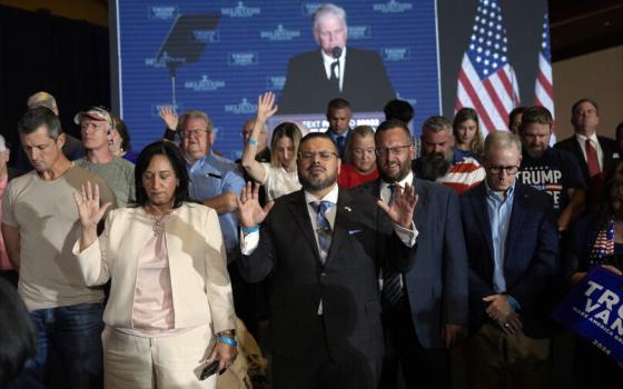 People stand with their hands raised, behind is a projector screen showing Graham.