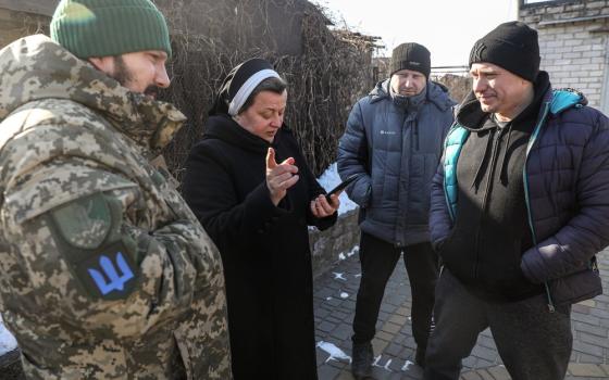 Habited nun wearing winter coat talks with three men outdoors.