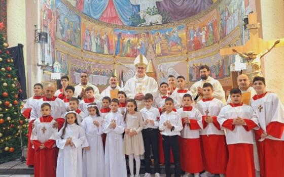 The cardinal vested in white, stands with many young peoples vested as acolytes, as well as the confirmands standing in middle.