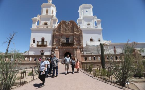 People walk out of large mission style church.