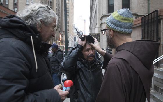 Franciscan Fr. Paul Lostritto marks a cross on the forehead of a homeless man on Ash Wednesday Feb. 14, 2018, at St. Francis Breadline in New York City. (CNS/Octavio Duran)