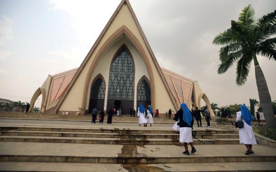 Habited sisters walking up steps to church building.