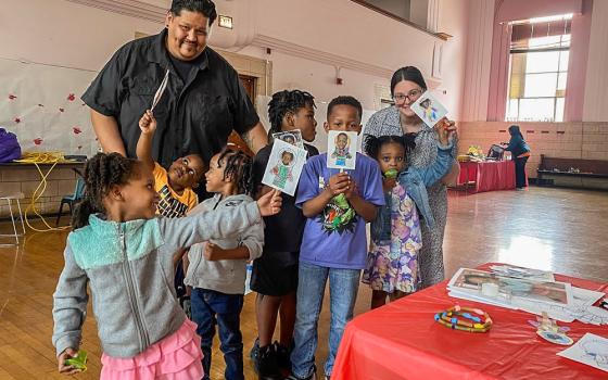 United Stand staff members Guillermo Rodriguez and Monica Kaczmarczyk pose with Chicago children displaying artwork they created at one of the nonprofit’s programs. (Courtesy of United Stand)