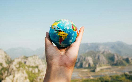 hand holding globe with mountains in the background