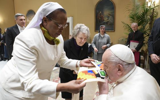 Pope Francis kisses a gift presented to him by Sr. Jane Wakahiu during an audience with the board of directors of the Conrad Hilton Foundation at the Vatican on Jan. 22, 2025. Standing to the right is Sr. Joyce Meyer.