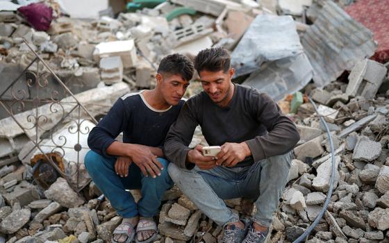 Palestinian twins Mahmoud and Ibrahim Al-Atout sit amid the rubble of their destroyed house after being reunited, in Jabalia, northern Gaza Strip, Jan. 29, 2025, following the ceasefire between Israel and Hamas,. The brothers were separated during the war when Ibrahim was displaced to the southern part of Gaza at Israel's order. (OSV News/Retuers/Osama Al-Arabid)