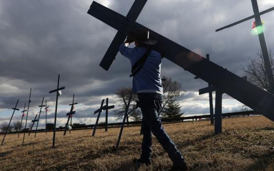 Marquez carries a cross on his shoulder, backgrounded by storm, gray sky.