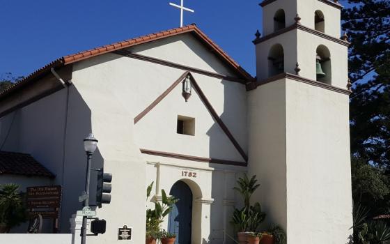 The front of church with bell tower and tiled roof. 