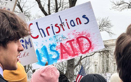 A woman waves a "Christians for USAID" poster Feb. 5, 2025, at a rally near the U.S. Capitol supporting the U.S. Agency for International Development, known as USAID. The agency, a top funder of Catholic Relief Services and other humanitarian work worldwide, is under threat as the Trump administration moves to dismantle it. (NCR photo/Rhina Guidos)