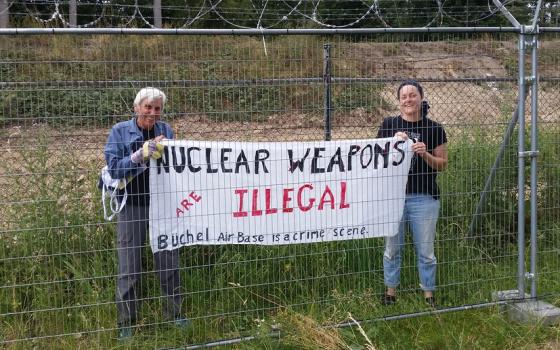 Eighty-one-year-old activist grandma Susan Crane (left), a Catholic Worker from Redwood City, California, takes a banner with her anti-nuclear proliferation message inside Büchel Air Force Base in Büchel, Germany. (Courtesy of Susan Crane)