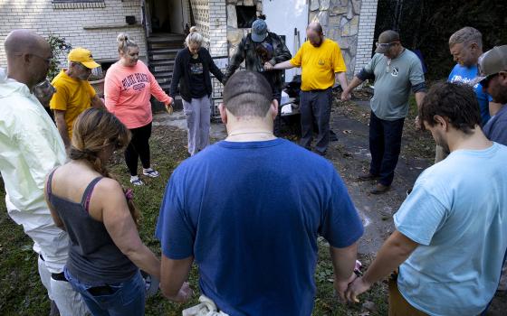 Group circled in prayer outside of house. 