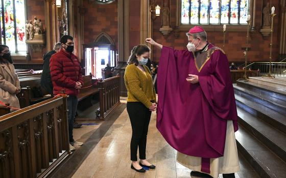 Bishop Edward B. Scharfenberger of Albany, N.Y., sprinkles ashes on parishioners.