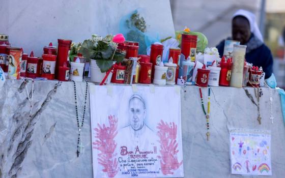 Well-wishers leave devotional items at the base of a statue of St. John Paul II outside Rome's Gemelli Hospital 