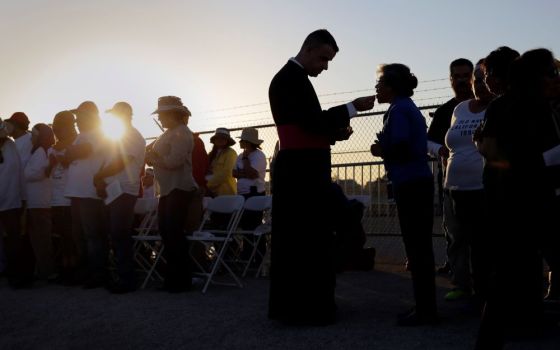 Migrants watching Pope Francis' Mass in Juarez, Mexico, from a levee along the banks of the Rio Grande in El Paso, Texas, take part in Communion, Feb. 17, 2016.