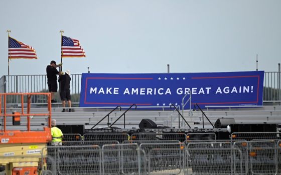 Following President Donald Trump's announcement he tested positive for the coronavirus disease, workers in Sanford, Florida, pull down signage at Orlando Sanford International Airport where the president was to have a rally Oct. 2. (CNS/Reuters/Phelan Ebe